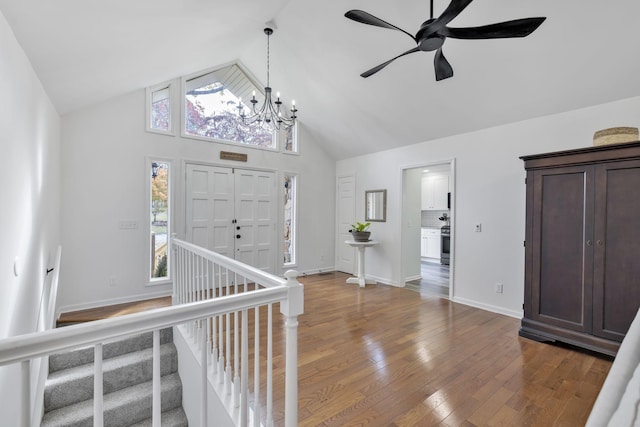 entryway with wood-type flooring, ceiling fan with notable chandelier, and high vaulted ceiling