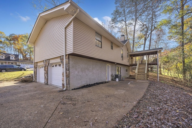 view of side of home with a deck, central AC unit, and a garage