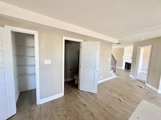 interior space with a spacious closet, a fireplace, baseboards, and light wood finished floors