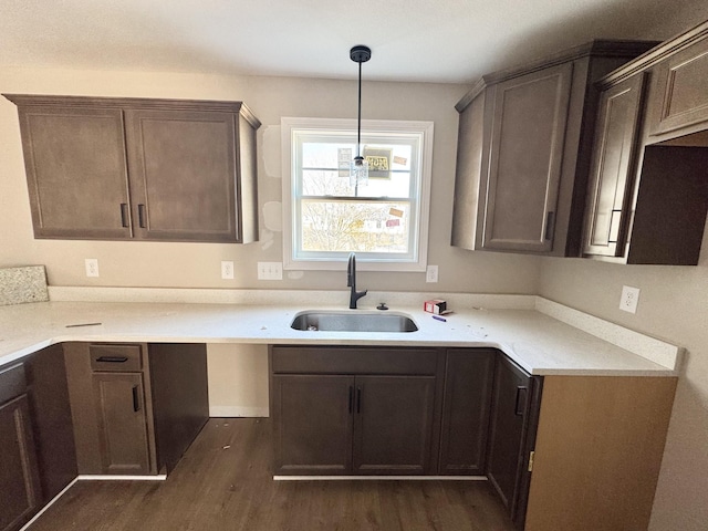 kitchen with decorative light fixtures, dark wood-style flooring, light countertops, and a sink