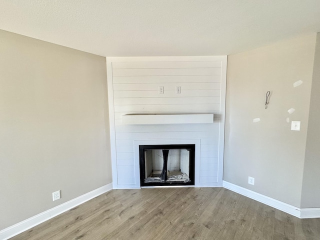 interior details featuring wood finished floors, a fireplace, baseboards, and a textured ceiling