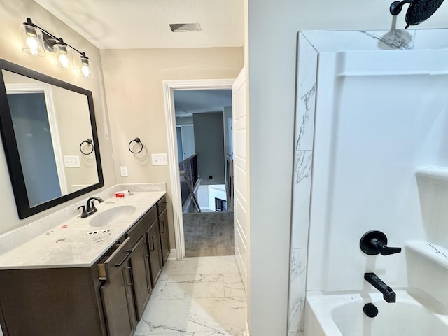 full bathroom with marble finish floor, a textured ceiling, vanity, and bathtub / shower combination