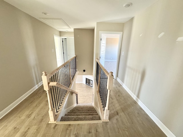 stairs featuring attic access, baseboards, and wood finished floors