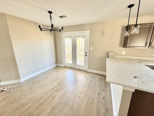 unfurnished dining area featuring baseboards, light wood-style floors, and a chandelier