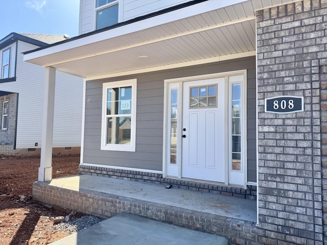 view of exterior entry with crawl space and a porch