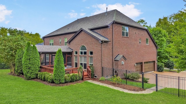 rear view of property featuring a garage, a lawn, and a wooden deck