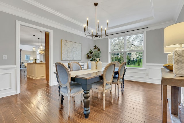 dining area featuring a raised ceiling, crown molding, hardwood / wood-style floors, and a notable chandelier