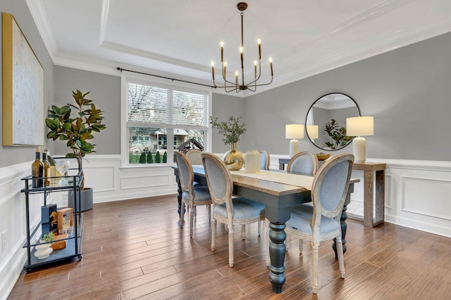 dining room featuring a raised ceiling, dark hardwood / wood-style flooring, ornamental molding, and a notable chandelier