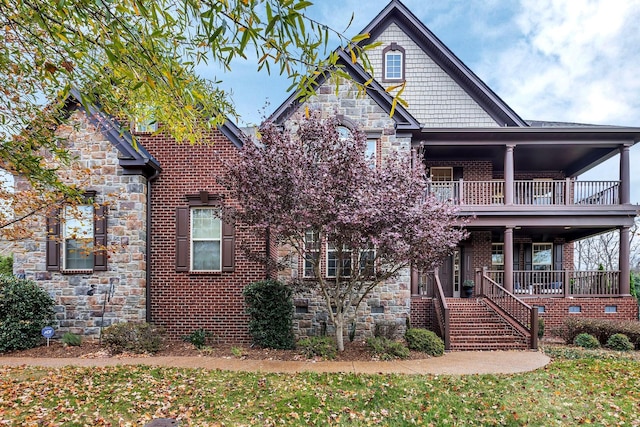 view of front of property with covered porch, a balcony, and a front lawn