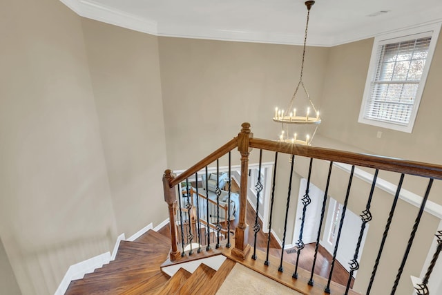 staircase with hardwood / wood-style floors, an inviting chandelier, and crown molding