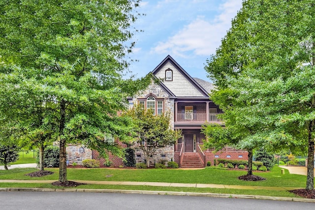 view of front of house with a balcony and a front lawn