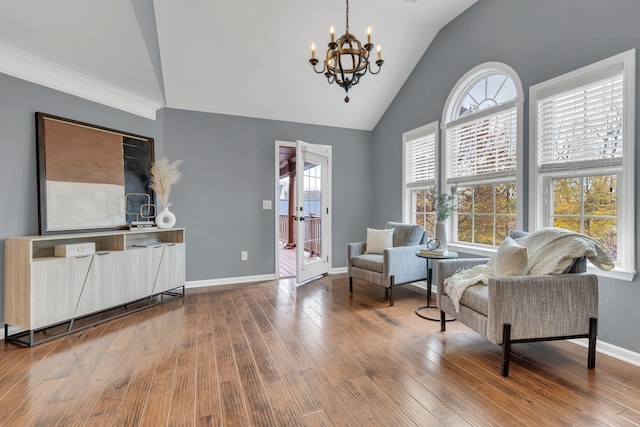 living area featuring wood-type flooring, vaulted ceiling, plenty of natural light, and a notable chandelier