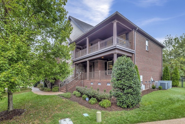 view of side of property featuring cooling unit, a balcony, and a yard