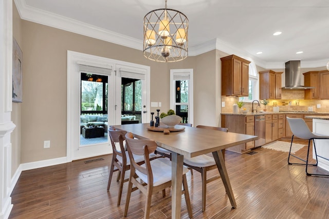 dining space with hardwood / wood-style floors, ornamental molding, a notable chandelier, and sink