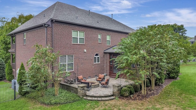 back of property with a fire pit, a patio area, and a lawn