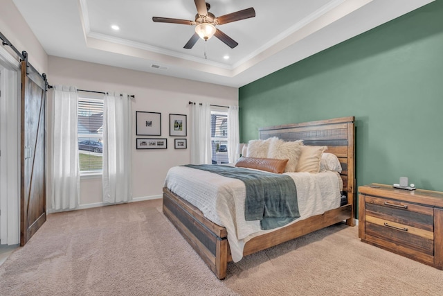 carpeted bedroom with a tray ceiling, a barn door, ceiling fan, and crown molding