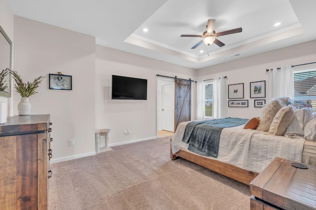 carpeted bedroom featuring a barn door, a tray ceiling, ceiling fan, and crown molding