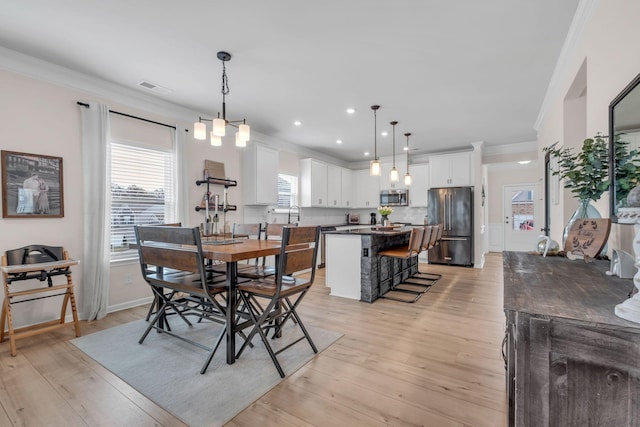 dining room with light wood-type flooring, crown molding, and sink