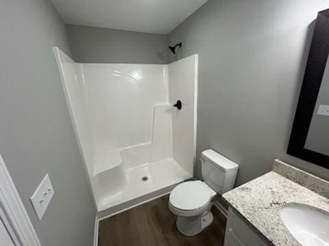 bathroom featuring wood-type flooring, vanity, toilet, and walk in shower