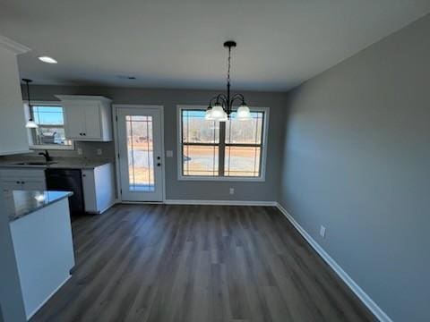 unfurnished dining area with sink, a chandelier, and dark hardwood / wood-style floors