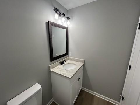 bathroom featuring vanity, hardwood / wood-style flooring, and toilet