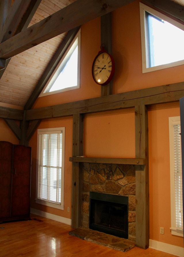 unfurnished living room with beam ceiling, a stone fireplace, and a healthy amount of sunlight