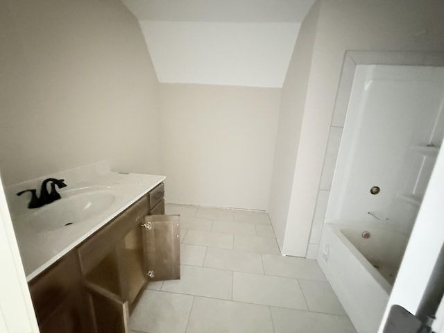 bathroom with lofted ceiling, vanity, a bathtub, and tile patterned floors