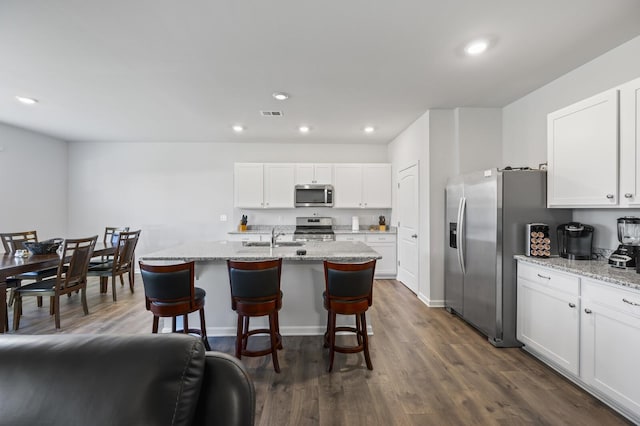 kitchen with a center island with sink, dark hardwood / wood-style floors, white cabinetry, and stainless steel appliances