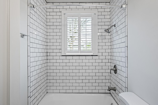 bathroom with toilet and tiled shower / bath