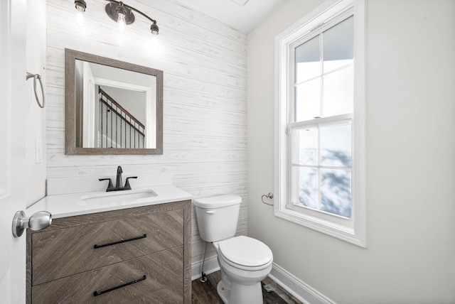 bathroom featuring hardwood / wood-style flooring, vanity, toilet, and wooden walls