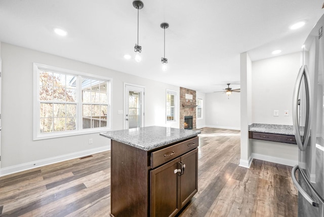 kitchen with stainless steel refrigerator, ceiling fan, dark hardwood / wood-style floors, pendant lighting, and dark brown cabinets