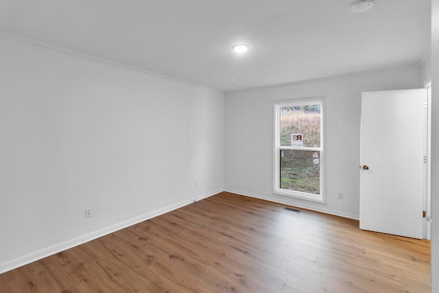 empty room with light hardwood / wood-style floors and crown molding