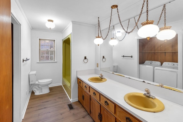 bathroom featuring independent washer and dryer, toilet, crown molding, and wood-type flooring