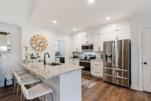 kitchen featuring kitchen peninsula, a kitchen bar, stainless steel appliances, sink, and white cabinetry