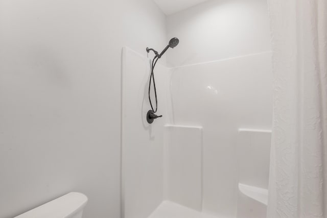 bathroom with a shower with shower curtain and toilet