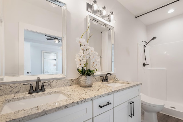 bathroom featuring vanity, a shower, hardwood / wood-style flooring, ceiling fan, and toilet