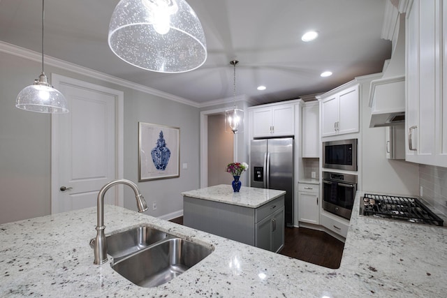 kitchen with stainless steel appliances, sink, pendant lighting, white cabinets, and a kitchen island