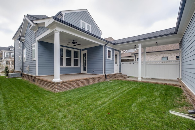 rear view of house with central air condition unit, ceiling fan, and a yard