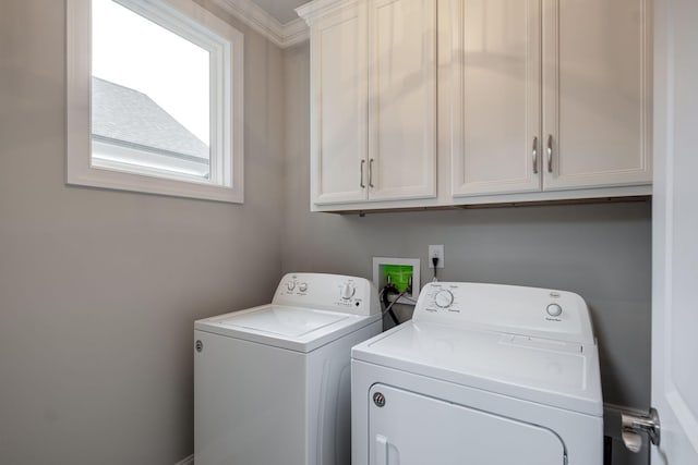 laundry room featuring washer and clothes dryer, cabinets, and ornamental molding