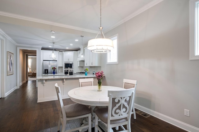 dining room featuring dark hardwood / wood-style floors, crown molding, and sink