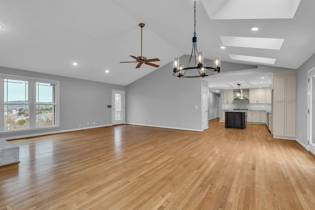 unfurnished living room with lofted ceiling with skylight, light hardwood / wood-style flooring, and ceiling fan with notable chandelier