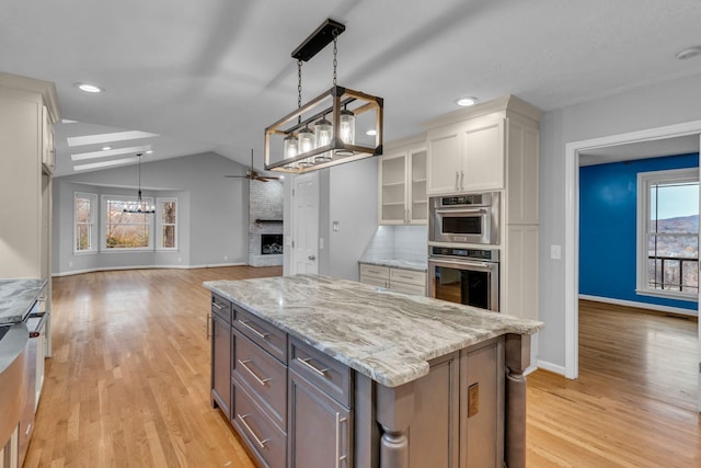 kitchen featuring white cabinetry, plenty of natural light, a kitchen island, and vaulted ceiling with skylight