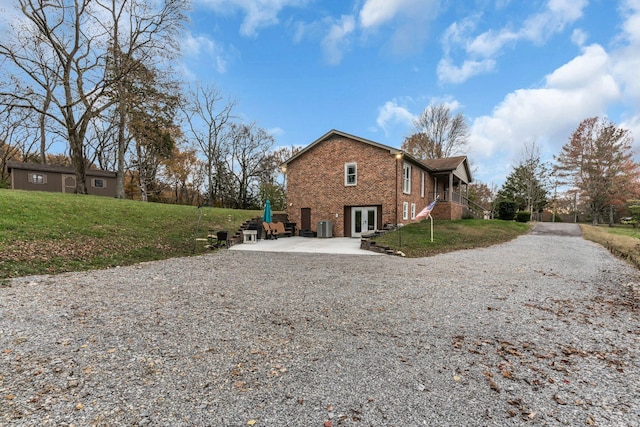 view of side of home featuring central AC, a yard, and french doors