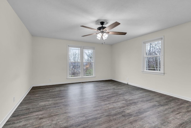 empty room featuring ceiling fan, plenty of natural light, and dark hardwood / wood-style floors