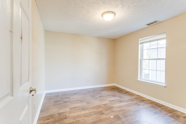 spare room with a textured ceiling and light hardwood / wood-style floors