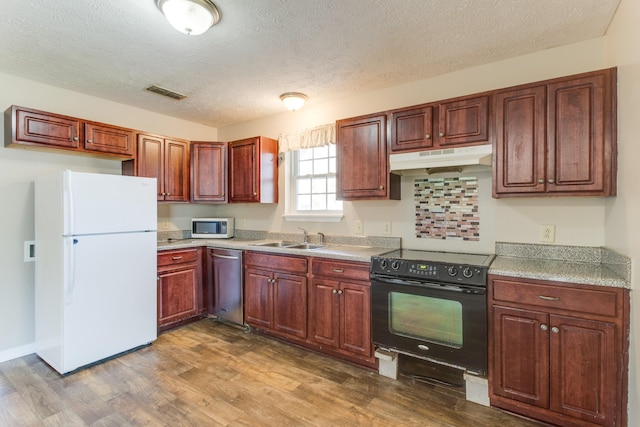 kitchen with hardwood / wood-style flooring, white appliances, sink, and a textured ceiling