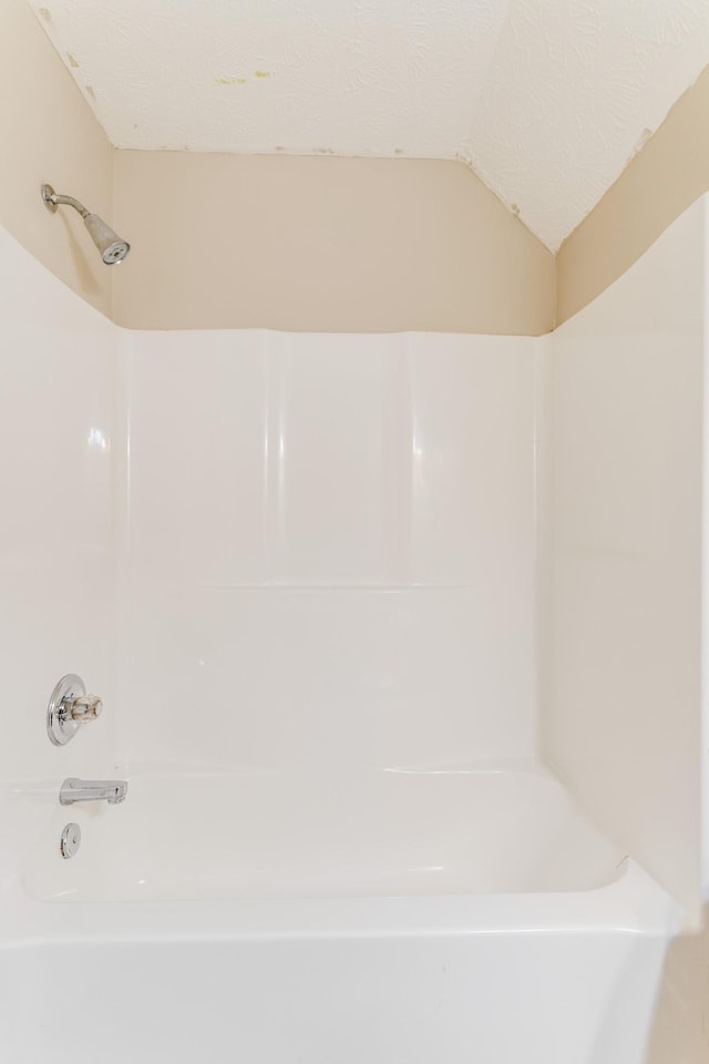 bathroom with a textured ceiling and vaulted ceiling