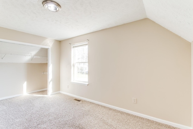 empty room featuring carpet, lofted ceiling, and a textured ceiling