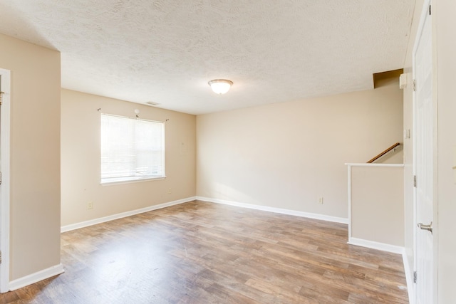 empty room featuring a textured ceiling and light hardwood / wood-style floors