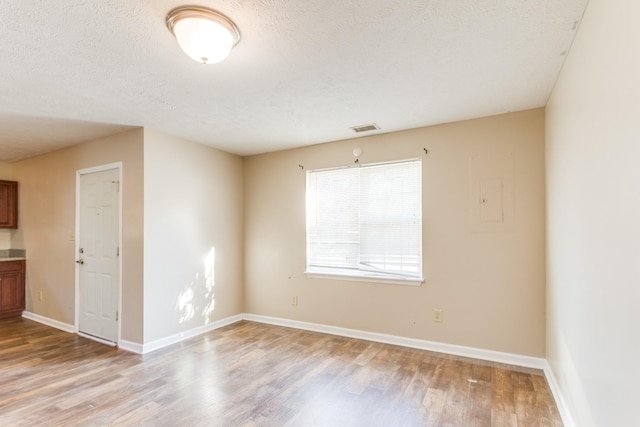 unfurnished room featuring a textured ceiling and light wood-type flooring